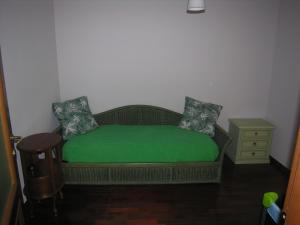 ein grünes Bett in einem Zimmer mit einem Nachttisch in der Unterkunft Appartamento signorile in Orbassano