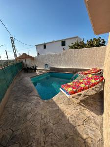 una piscina con 2 tumbonas junto a una casa en Villa Rafael, en Puente del Obispo