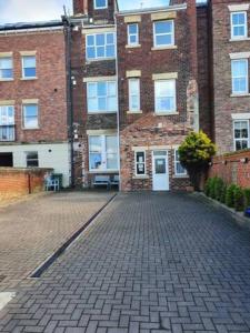 a brick building with a brick driveway in front of it at Northcliffe Sea View in Sunderland