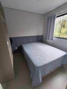 um pequeno quarto com uma cama e uma janela em Residencial Brisa do Mar em Bombinhas