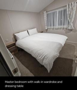 a bedroom with a white bed with walk in wardrobe and dressing table at Luxuary Static Caravan Sleeps 6 Coopers Beach - Luxurious Get Away in East Mersea