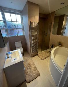 een badkamer met een bad, een wastafel en een toilet bij The Victorian Rooms in Surbiton