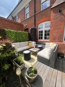 a patio with a white couch and chairs on a wooden deck at The Victorian Rooms in Surbiton