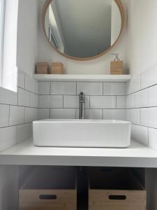 La salle de bains est pourvue d'un lavabo blanc et d'un miroir. dans l'établissement Biscarrosse Lac - Maguide -Modern Chalet, à Biscarrosse