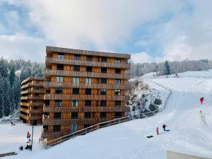 un bâtiment sur une piste de ski avec des personnes dans la neige dans l'établissement Sunny Stenna Selva 3-room ski-in ski-out apartment right by the slopes & lifts, à Flims