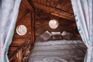 a bed in a wooden cabin with two windows at Apple Tree Cabin (Friendship Land) 