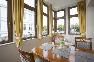 a dining room with a wooden table and windows at Haus Meerblick - 04 in Ahlbeck