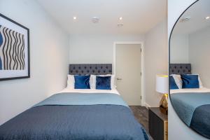 um quarto com uma cama com lençóis azuis e um espelho em Cosy 3 Bed by Old Trafford By Valore Property Services em Manchester