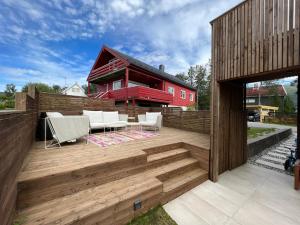 a wooden deck with white chairs and a red house at Tromsø Town House in Tromsø