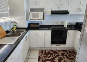 a kitchen with white cabinets and a sink and a microwave at Casa Uvongo 110 in Uvongo Beach