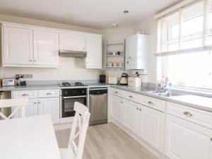 eine weiße Küche mit weißen Schränken und einem Tisch in der Unterkunft 1 Camperdown Lodge in Salcombe