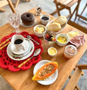 einen Holztisch mit einem Teller Essen und einer Tasse Kaffee in der Unterkunft Pousada Bilica in Arraial d'Ajuda