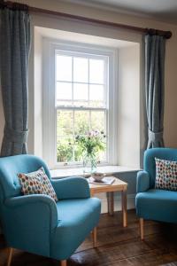 a living room with two chairs and a window at Rosehip Cottage in Holbeton