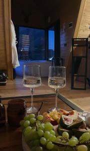 two wine glasses sitting on a table with a plate of grapes at Vista cottage in Stepantsminda