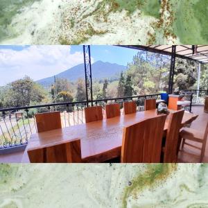 a table with chairs and a view of a mountain at Vila Dinar Mountain View Lembang in Lembang