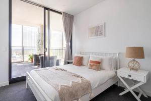 a white bedroom with a bed and a large window at The Occidental Pearl in Sydney