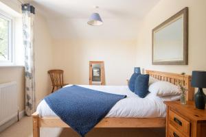 a bedroom with a bed with a blue blanket on it at Wren Cottage in Holbeton
