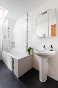 a white bathroom with a sink and a bath tub at Wren Cottage in Holbeton