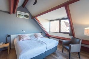 a bedroom with a bed and a chair and a window at Hotel Faber in Zandvoort