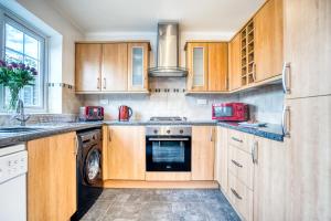 a kitchen with wooden cabinets and a washer and dryer at Pangbourne House in Higham on the Hill