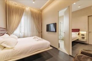 Schlafzimmer mit einem weißen Bett und einem TV in der Unterkunft N18 luxury boutique apartment with a private pool & spa in Mailand