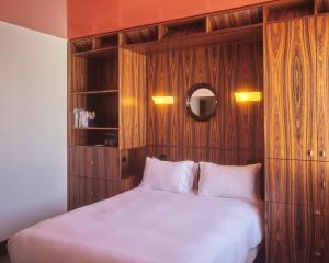 a bedroom with a large white bed with wood paneling at Hôtel Présent - Entrée autonome, réception en ligne - Encore Mieux in Arles