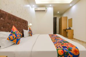 a bedroom with a large white bed with colorful pillows at FabHotel Crown Star in Dehradun