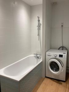 a white bath tub with a washing machine in a bathroom at LES 3 MARMOTS in Gérardmer +4 photos