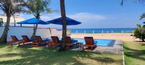 a group of chairs and umbrellas next to the beach at Tropical Beach House Hikkaduwa in Hikkaduwa