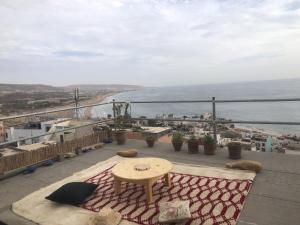 een balkon met een tafel en uitzicht op de oceaan bij Hostel blue house Taghazout in Taghazout