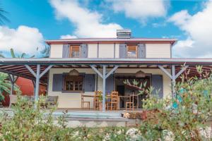 a white house with a porch and chairs at Evasion tropicale villa créole avec piscine et bungalow in Saint-Louis