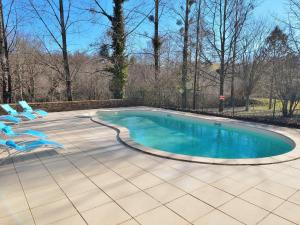 una piscina con 2 sillas azules al lado en Serene Holiday Home in Cussac with Private Terrace Barbeque, en Cussac
