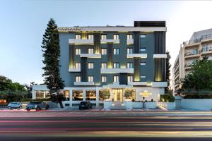 a building with a parking lot in front of it at Glyfada Riviera Hotel in Athens