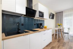 Modern Studio in Resort & SPA Dziwnów by Renters في جيفنوف: مطبخ مع دواليب بيضاء ومغسلة