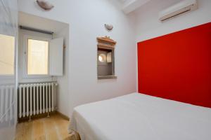 a bedroom with a white bed and a red wall at Spada Apartment in Florence