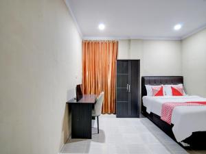a bedroom with a bed and a desk and a window at OYO 93087 Wisma Apel Syariah in Parit