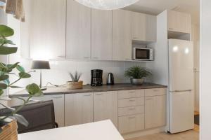 a kitchen with white cabinets and a white refrigerator at Tunnelmallinen kaksio in Jyväskylä +8 photos