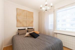 a bedroom with a bed with a chandelier and a window at Tunnelmallinen kaksio in Jyväskylä