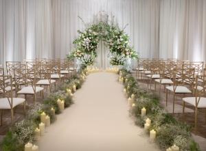 a wedding aisle with white flowers and candles at The Westin London City in London
