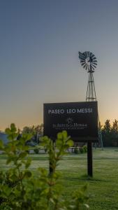 una señal en un campo con un molino de viento en Un Alto en la Huella - Hotel Spa & Wellness Resort en San Antonio de Areco