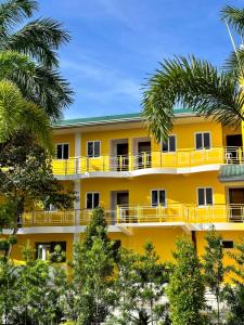 un edificio amarillo con árboles delante de él en Dreaming Forest Hotel - Libjo, Batangas en Batangas