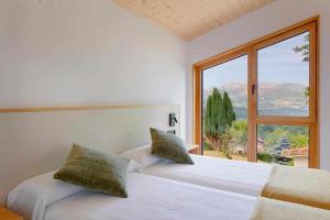 a bedroom with two beds and a large window at El Balcón del Sueve in Melarde