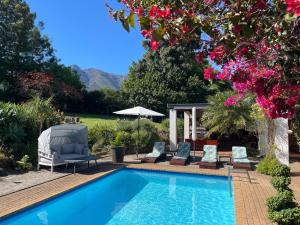 a swimming pool with two chairs and a table at Marula Lodge in Swellendam
