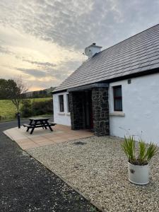 a white building with a picnic table in front of it at Tavnaghoney Cottages in Cushendall