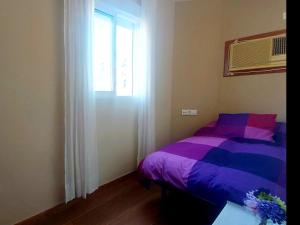 um quarto com uma cama roxa e uma janela em Enladrillada.Parking Incluido.Cuna del Flamenco em Sevilha