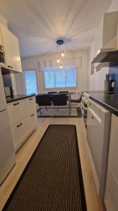 a kitchen with white cabinets and a black rug at Stylish apartment in town centre in Sotkamo