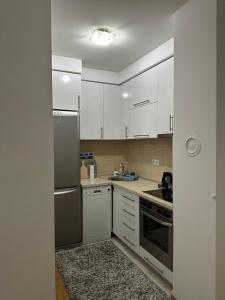 une cuisine avec des armoires blanches et des appareils en acier inoxydable dans l'établissement Nelly, à Sarajevo