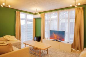 a living room with a couch and a large window at Yuzawa Onsen Lodge 1min to LIFT House in Seki