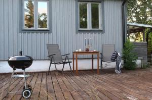 a grill and chairs and a table on a deck at Cosy guesthouse in the countryside, with breakfast in Malmö