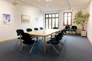 una sala de conferencias con mesa de madera y sillas en Tagungs- und Bildungszentrum Steinbach/Taunus, en Steinbach im Taunus